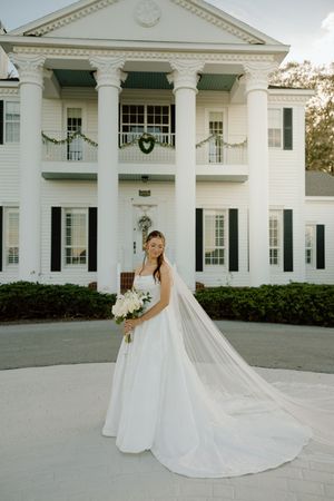 A stunning white colonial mansion serves as backdrop for elegant bridal portraits.