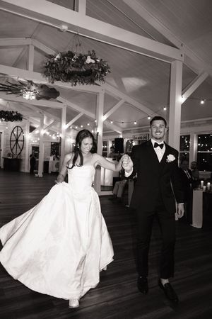 Elegant black and white photo of newlyweds walking through a beautifully decorated venue.