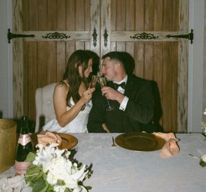 Wedding reception scene with guests celebrating at wooden tables.
