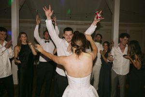 Wedding reception guests dancing and celebrating in a dark indoor venue.
