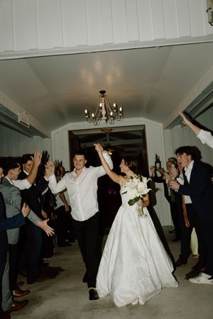 Wedding reception celebration with guests cheering as newlyweds make their grand exit.
