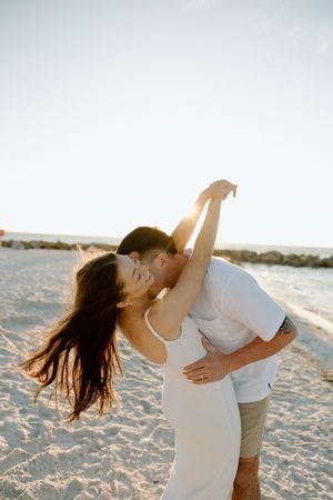 A romantic dance sequence on a sandy beach at sunset with flowing white dress.