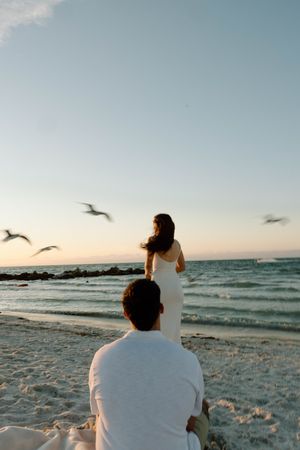 A peaceful beach scene at sunset with seagulls flying over the ocean.