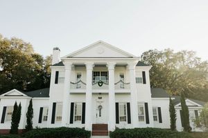 Elegant white colonial mansion with black shutters and classical columns photographed at sunset.