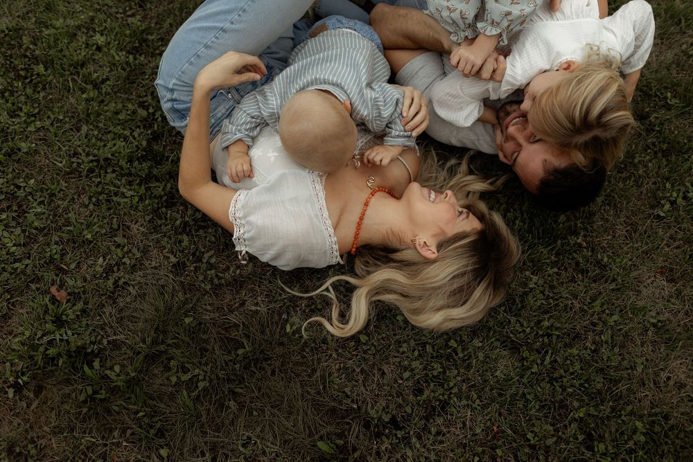 A couple lies together on grass in a romantic embrace during a photo shoot.