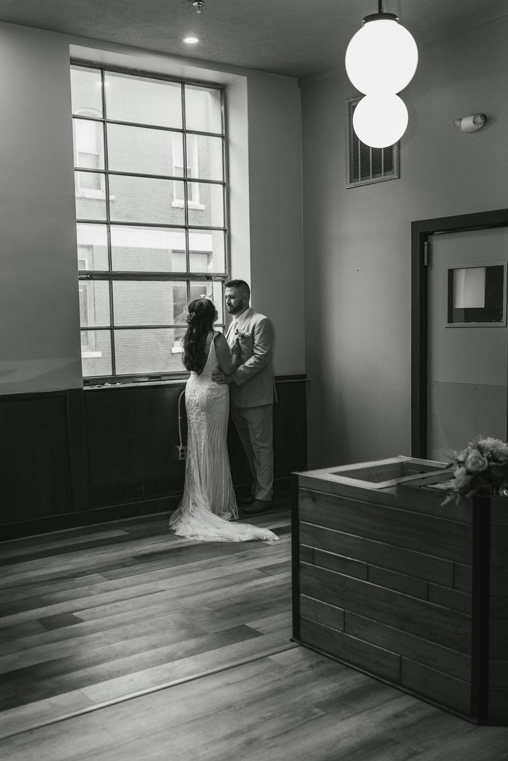 Black and white photo series showing a couple in wedding attire sharing an intimate first look moment in a modern interior space.