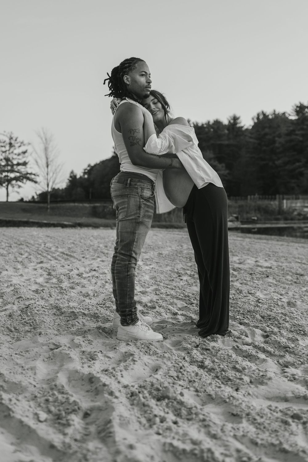 A sequence of three black and white photos showing two people sharing a tender moment on a sandy beach.