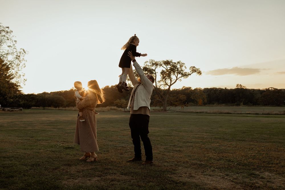 Silhouetted couple walking through open field during golden hour sunset.