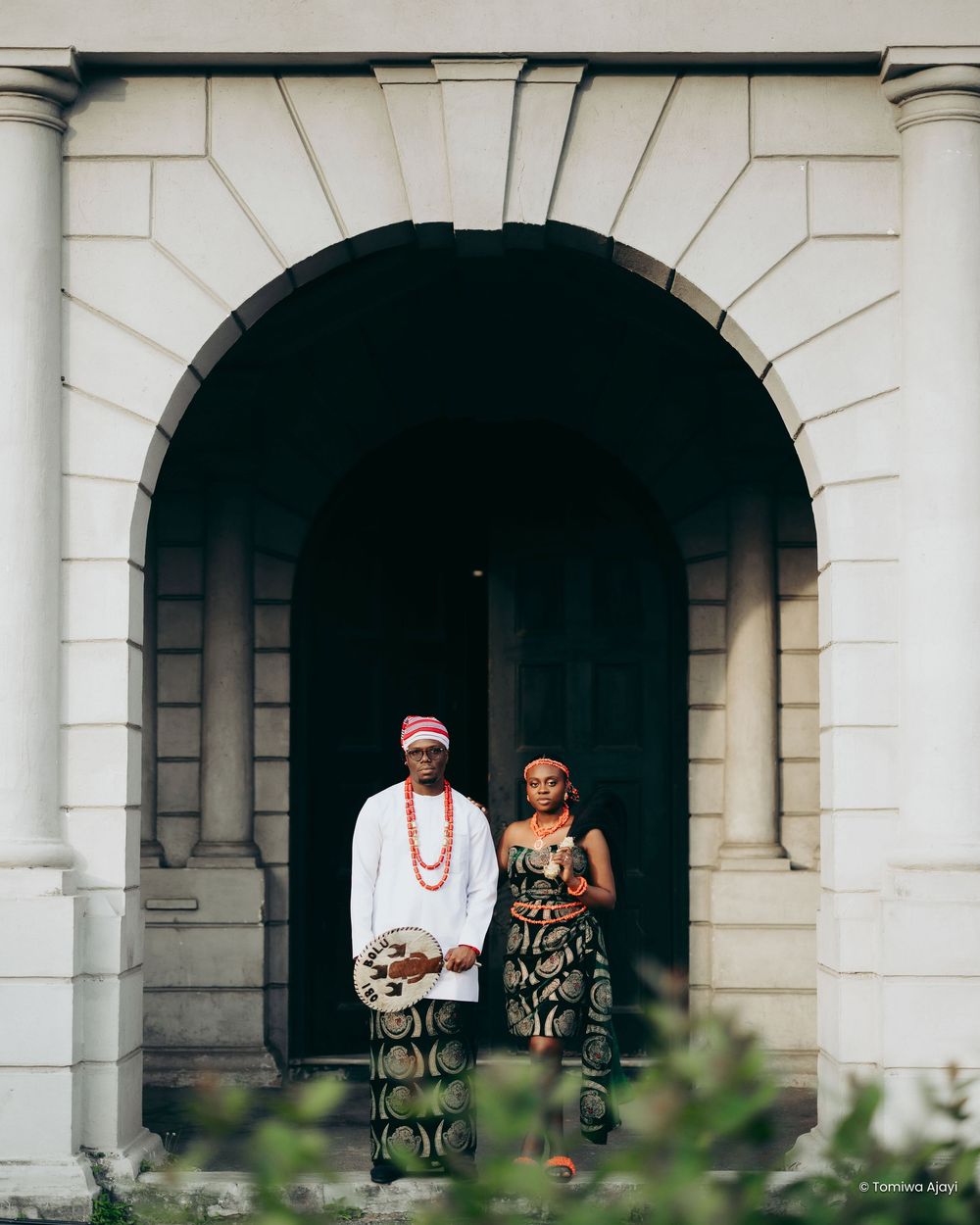 Architectural wedding portrait under white stone archways and columns.