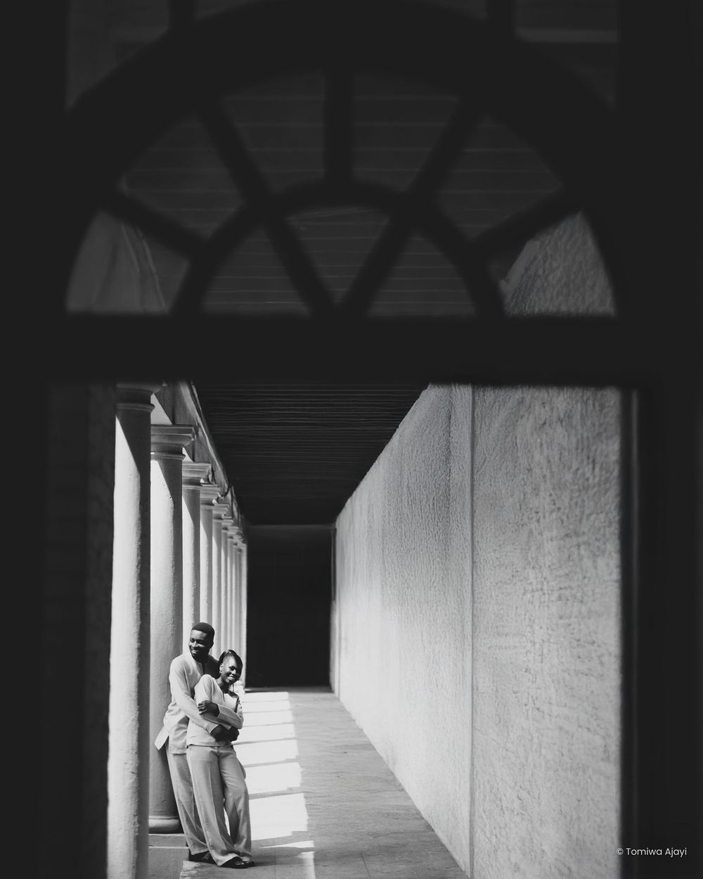 Black and white wedding photos captured in a dramatic corridor with natural light.