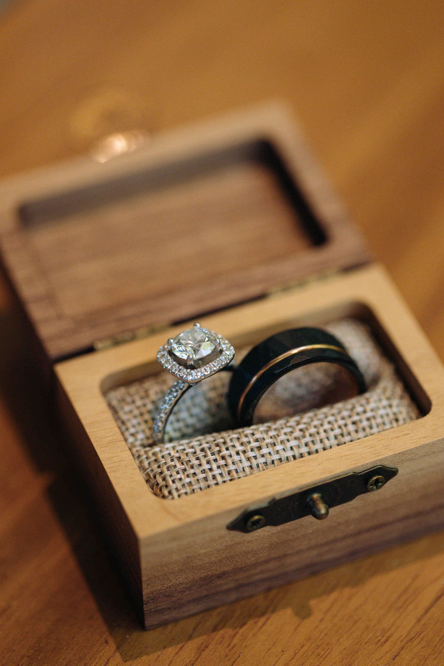 Close-up sequence of a diamond engagement ring nestled in a wooden box with textured fabric lining.