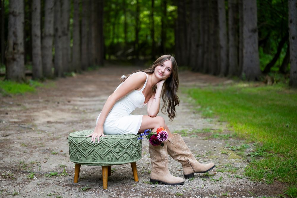 Rustic outdoor portrait featuring a vintage teal ottoman and boots along a tree-lined path.