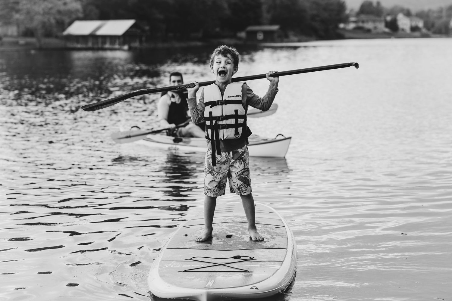 Black and white sequence of paddleboarding on calm water.