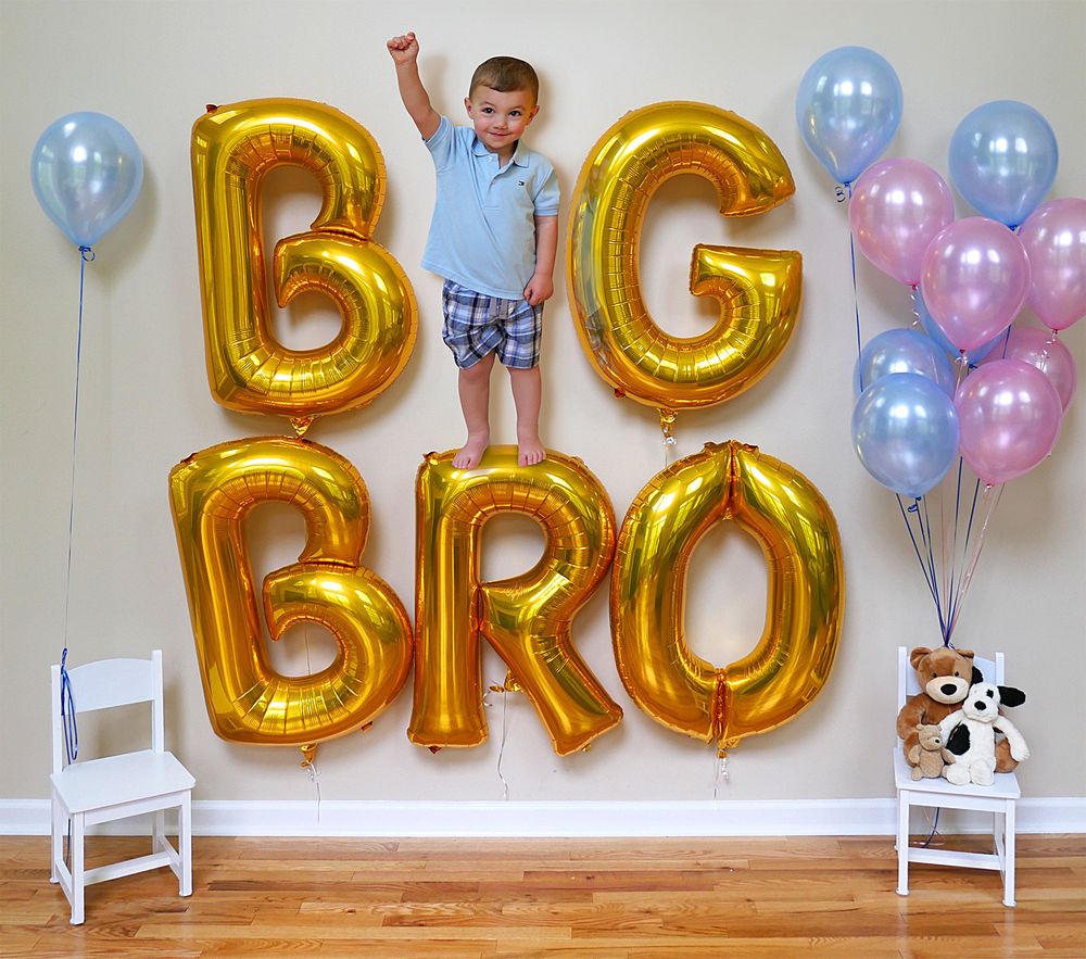 A birthday party decoration setup with gold letter balloons and blue and pink balloons against a white wall.