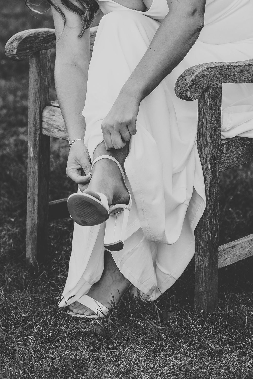 Close-up black and white photo series showing someone putting on white shoes while sitting on a wooden bench.