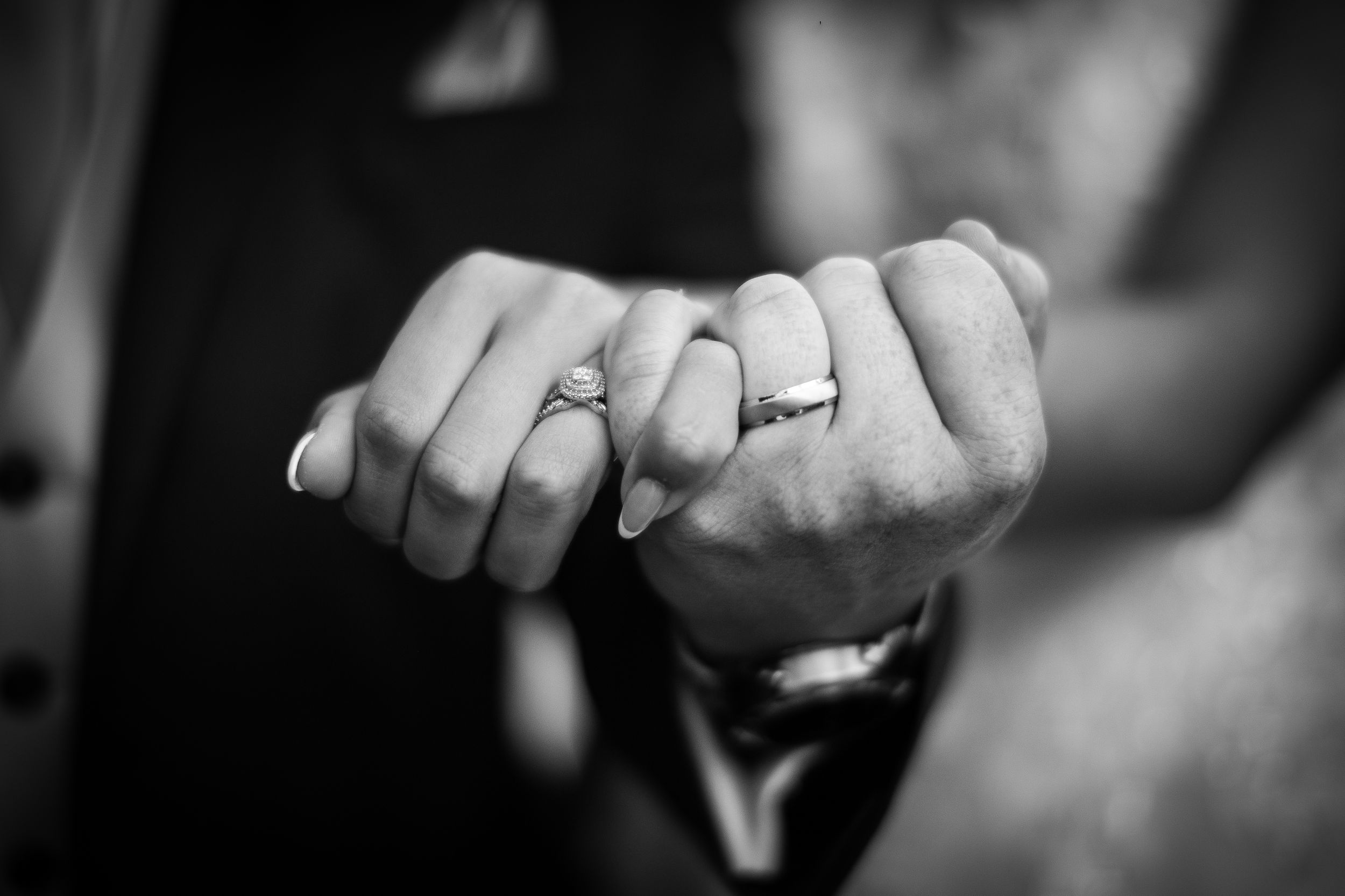 Black and white detail of wedding rings and hands.