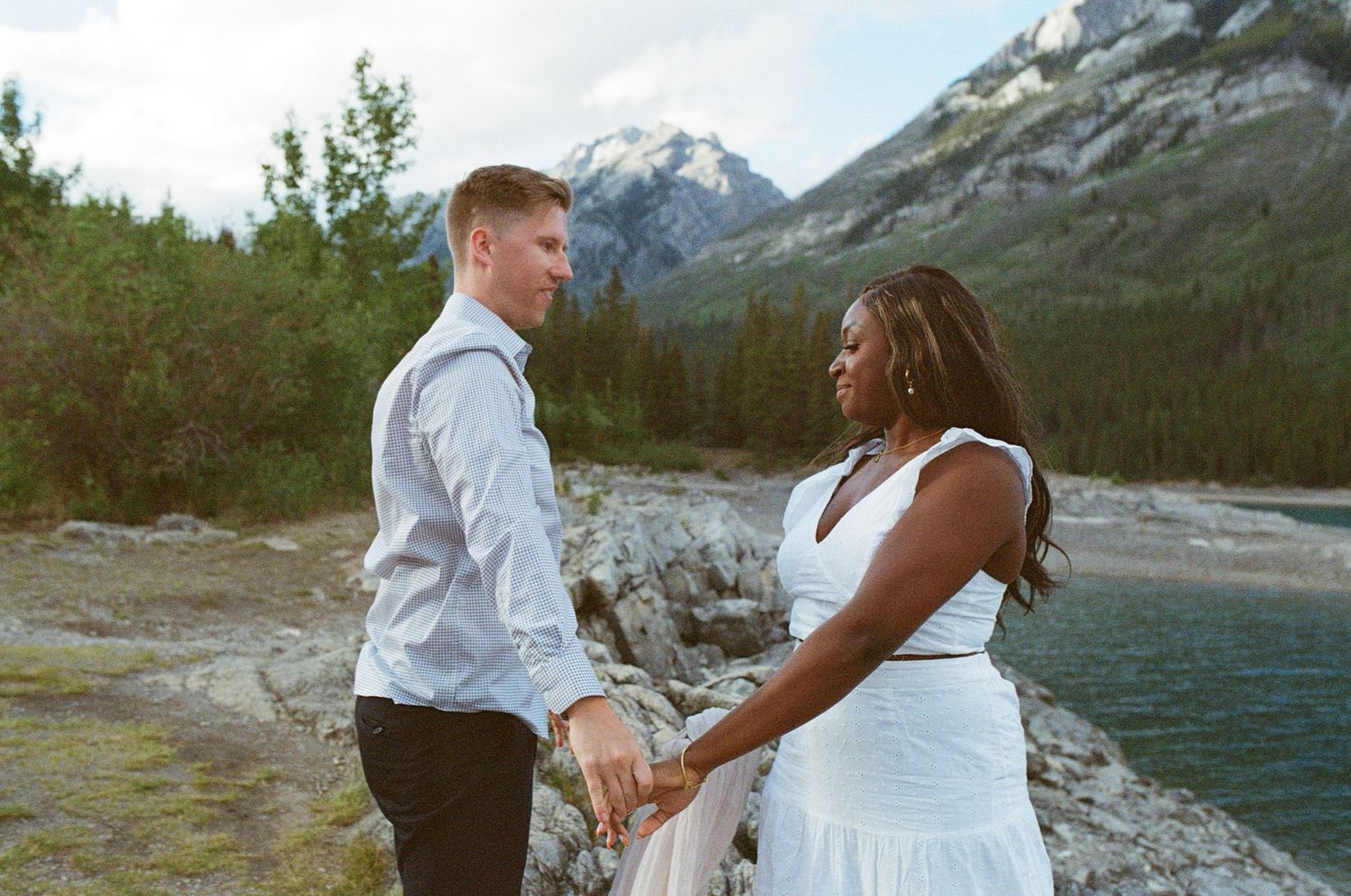 35 mm film photo of bride and groom holding hands on a rocky outcrop in Banff with mountains all around them