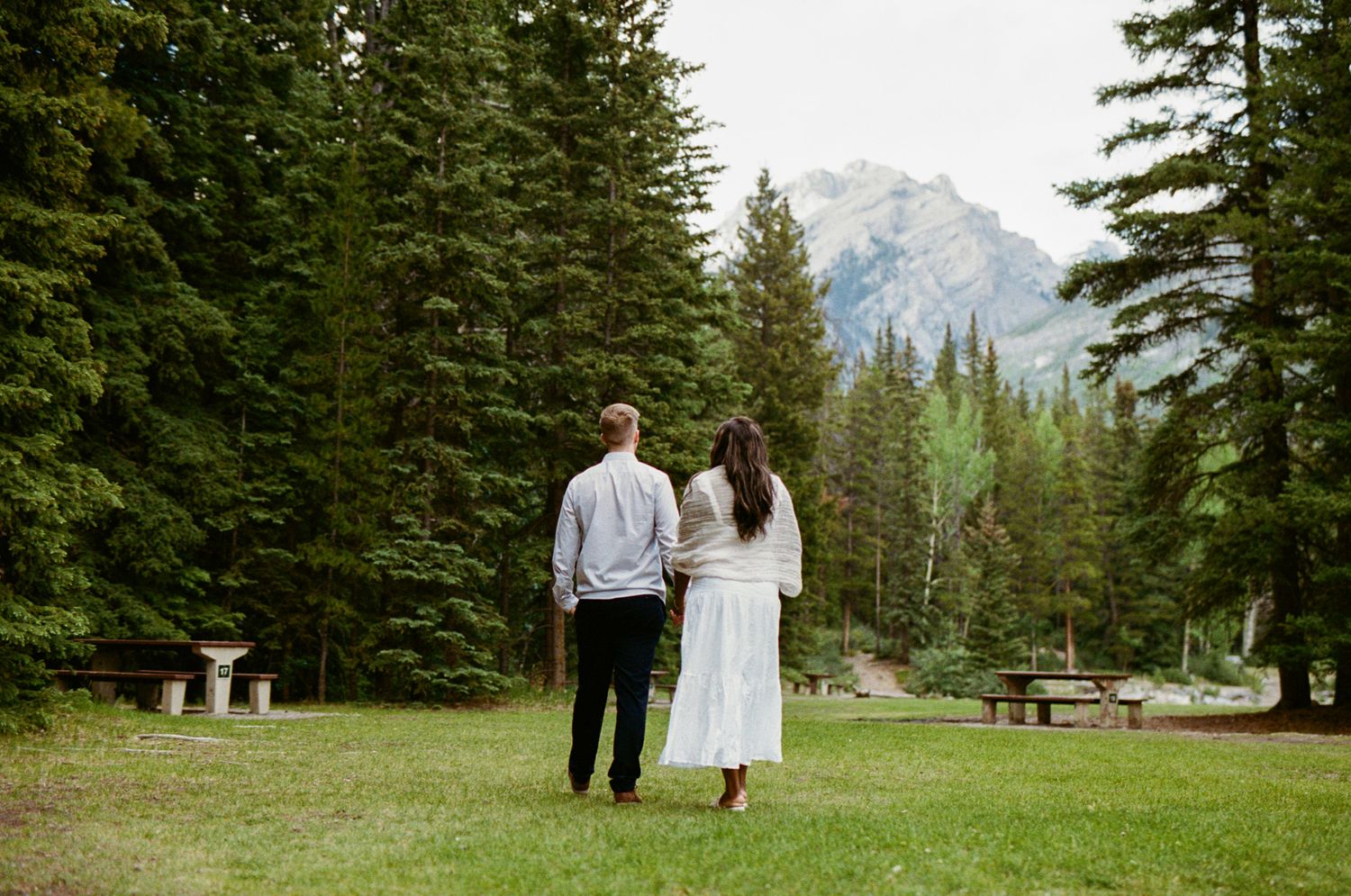 35 mm film photo of Bride and Groom walking through a lush green campground in Banff National Park