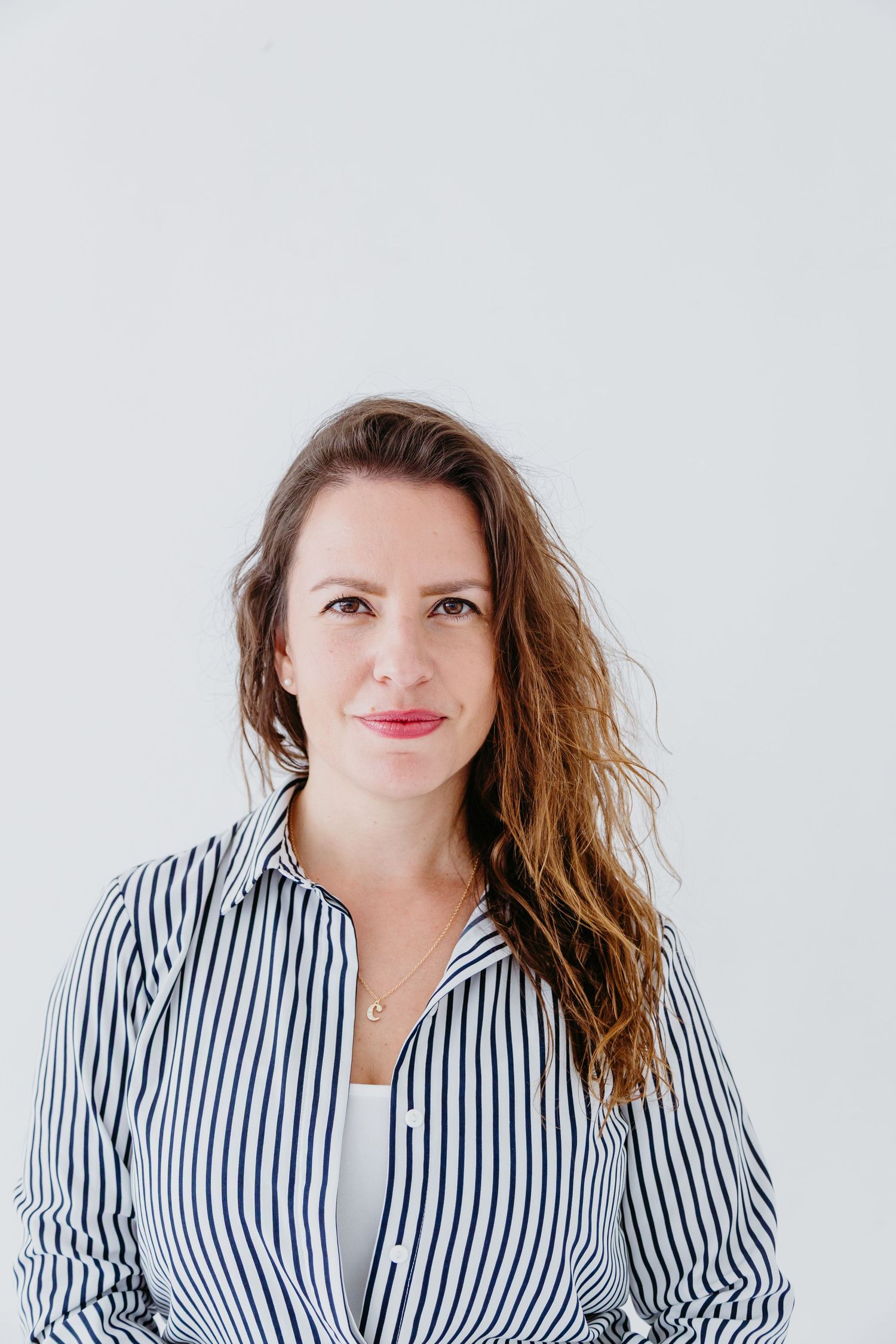 Professional portrait against white background wearing a black and white striped button-up shirt.