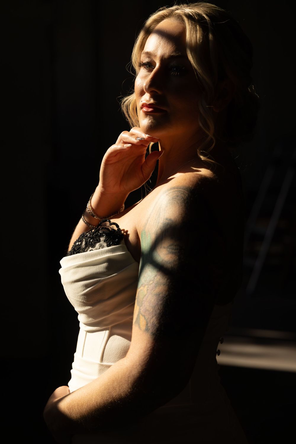 Artistic portrait in low key lighting showing a figure against dark background with dramatic shadows.