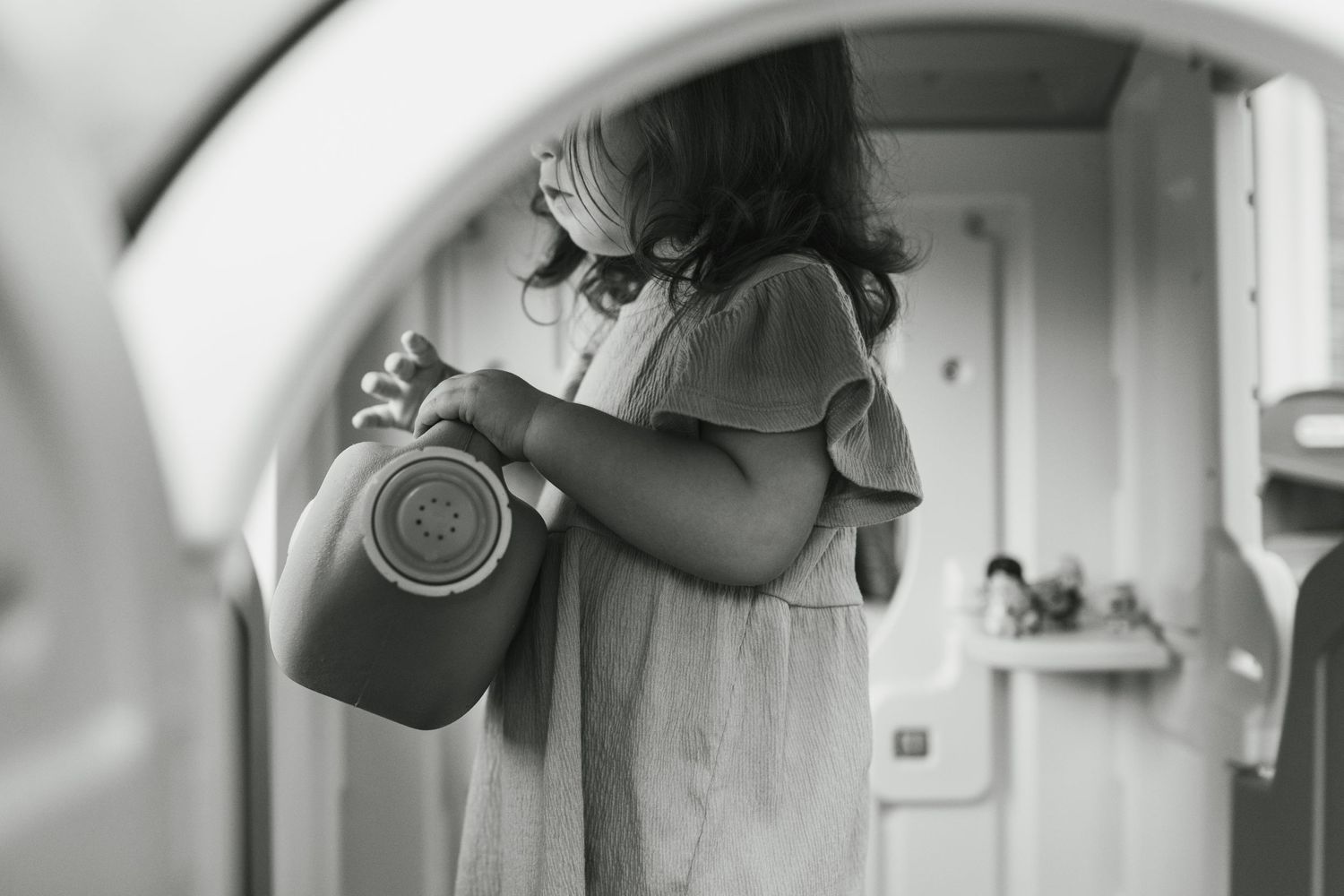 Black and white photo of someone taking a picture in a circular mirror reflection.