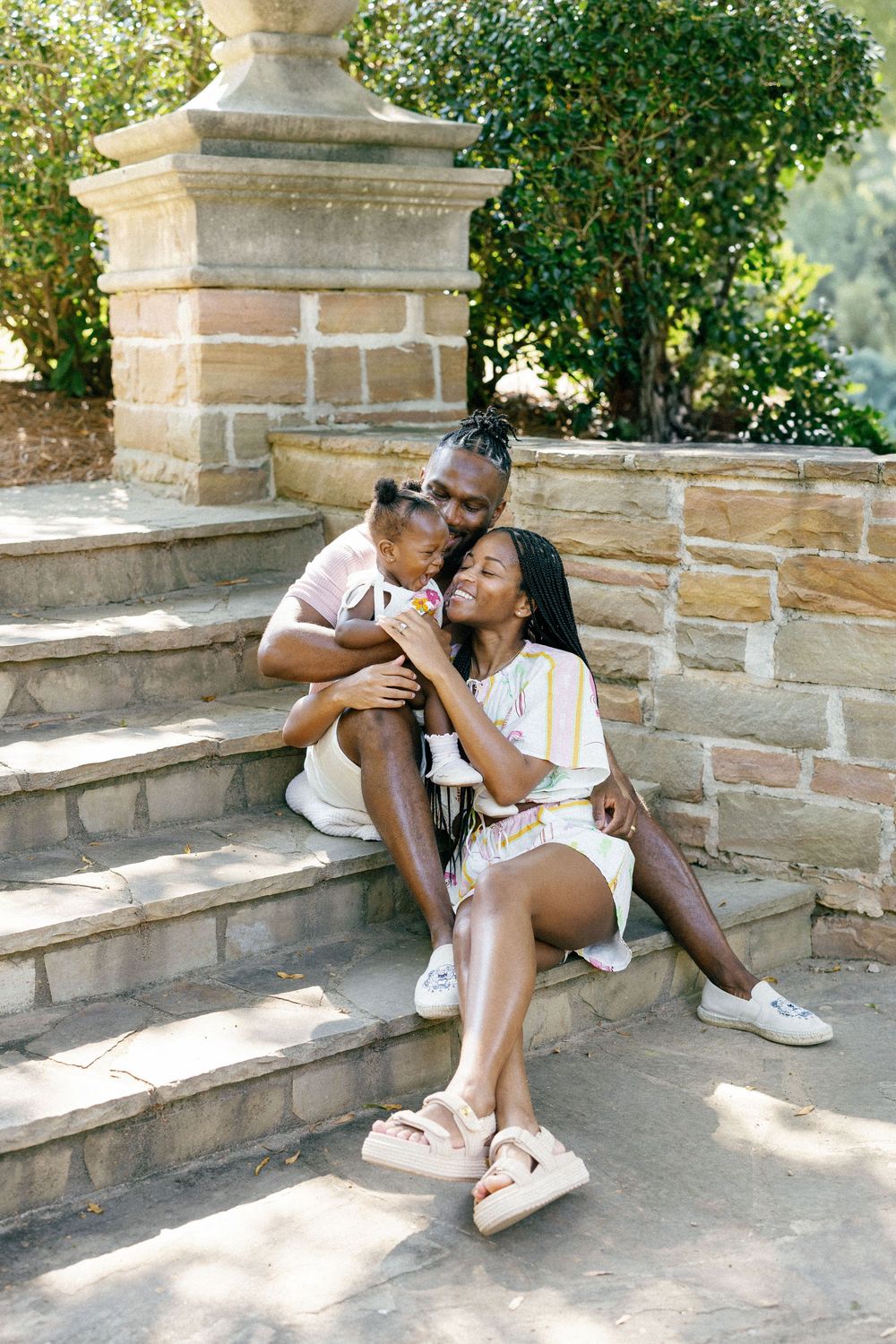 A loving family shares tender moments together while relaxing on outdoor stone steps.