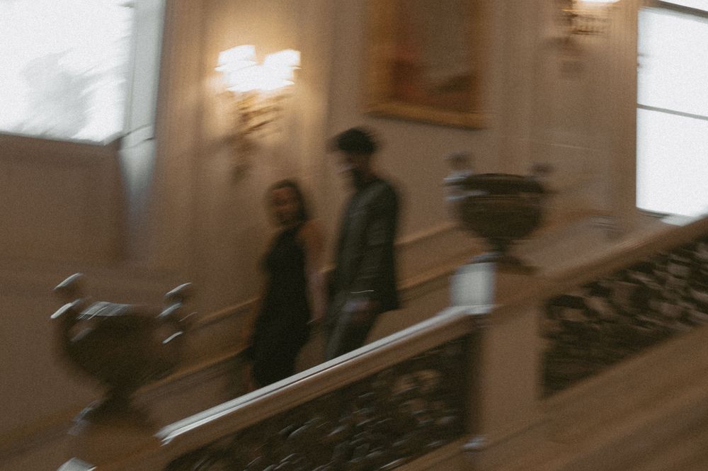 Motion blur photograph of people walking in an elegant hallway with warm lighting.