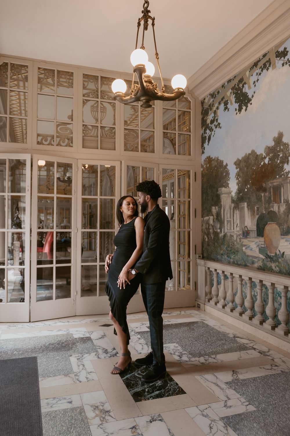 Romantic scene in vintage sunroom with antique chandelier and scenic wallpaper murals.