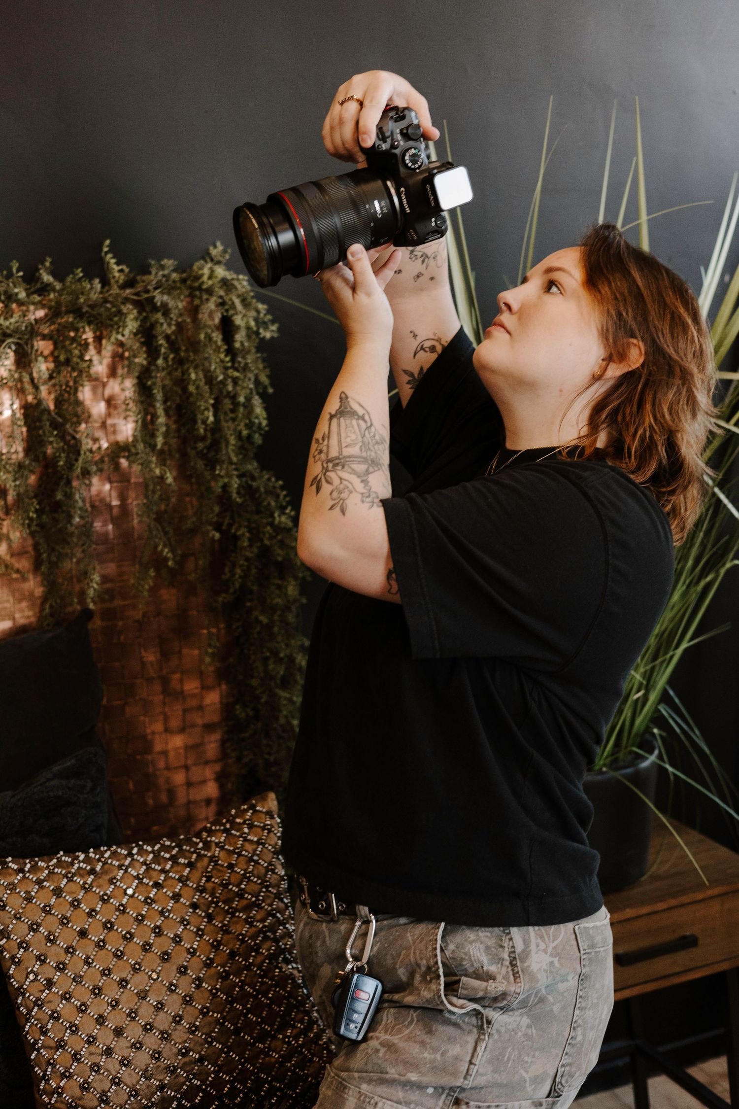 Person in black shirt and jeans drinks from a bottle against a dark background with decorative elements.