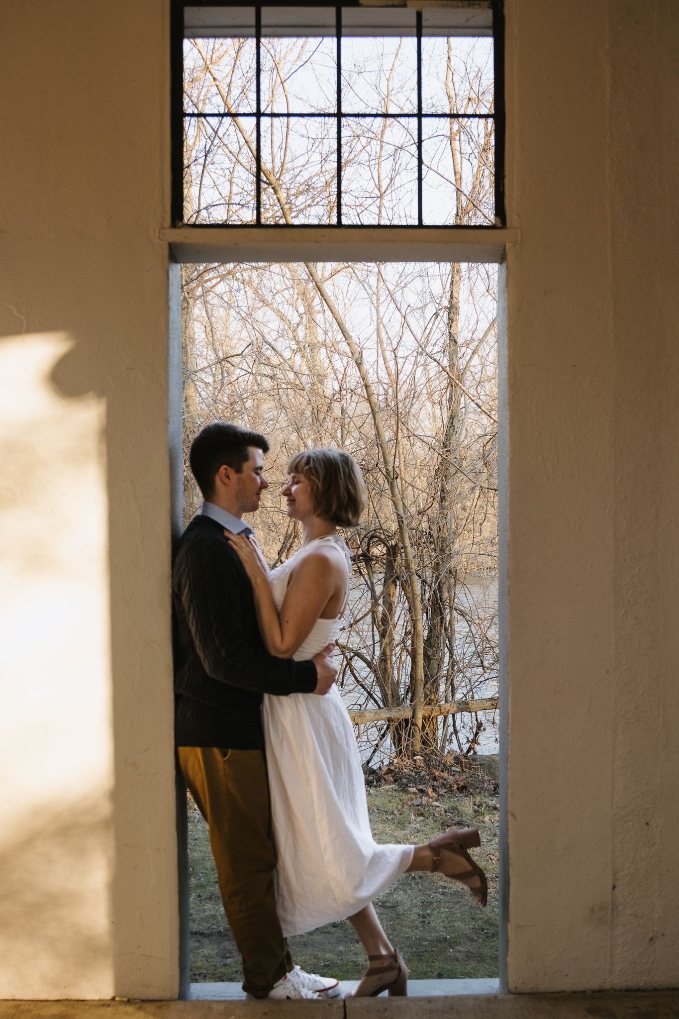 A man and woman embracing in engagement photos taken at Island Park in Ann Arbor.