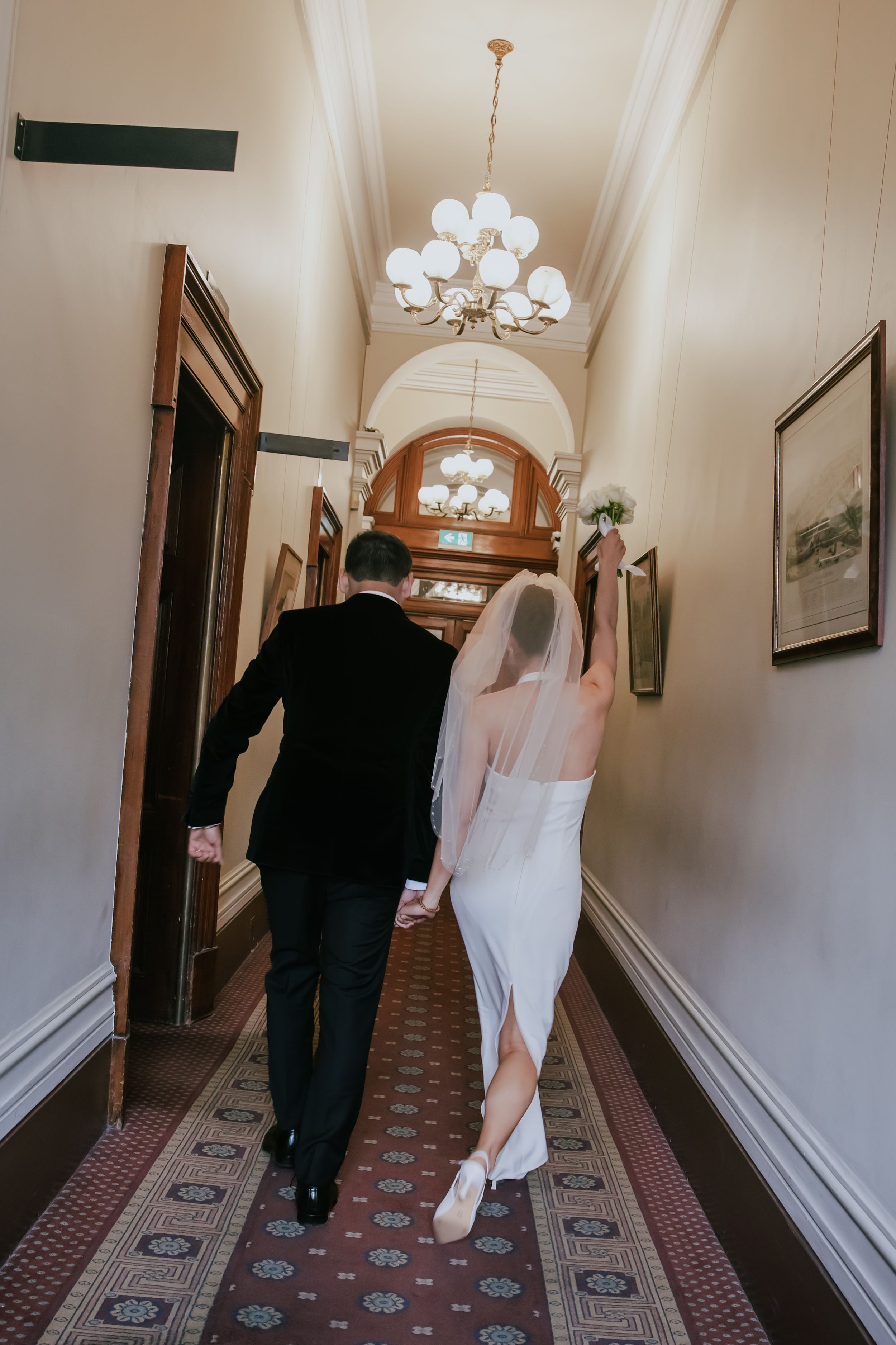 A sequence of four photos shows a couple walking down an elegant hotel hallway with patterned carpet and wall sconces.