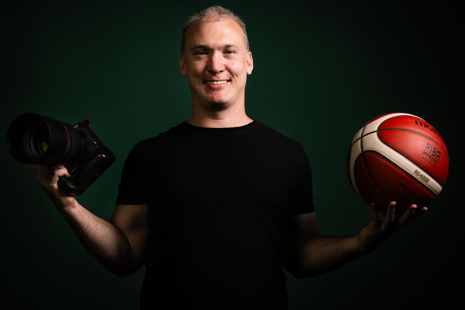Dramatic sports portrait series with basketball and football in dark studio setting.
