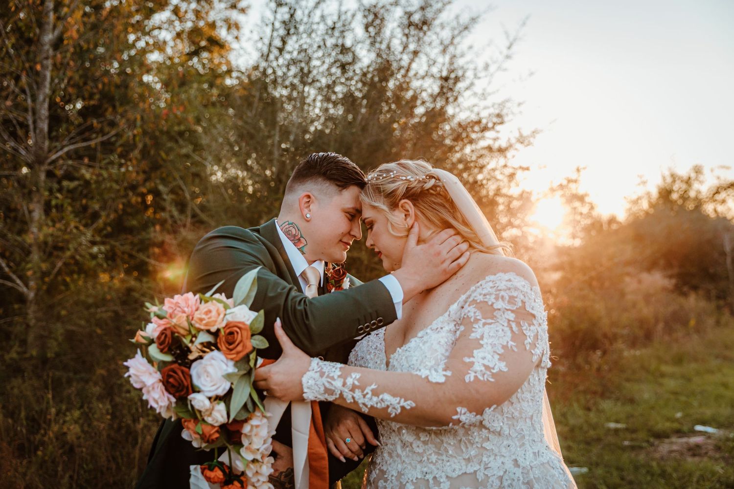 A romantic wedding couple embraces during golden hour sunset in an outdoor autumn setting with fall foliage.