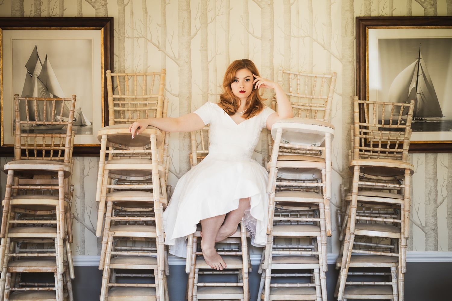 A sequence of white rocking chairs arranged in a line against a rustic wooden wall with vintage styling.