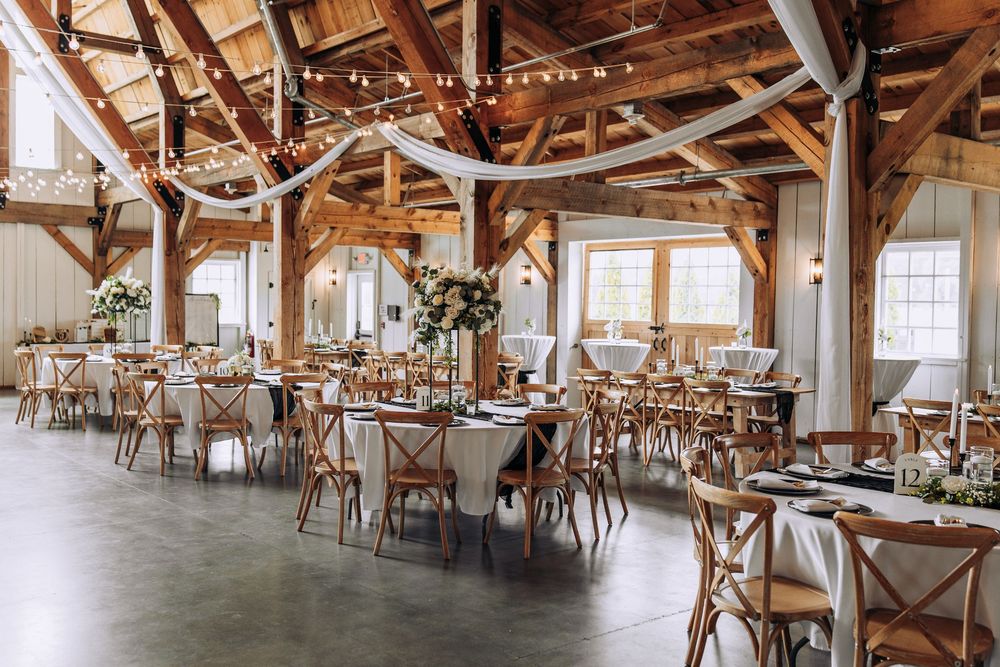 Rustic barn wedding reception with wooden beams, string lights, and floral centerpieces.