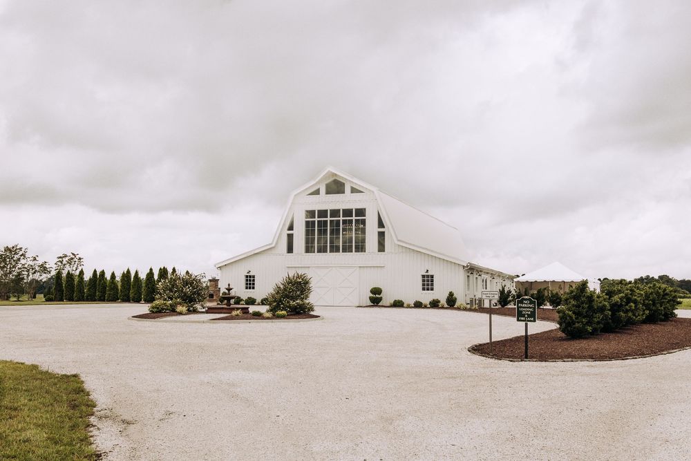 White barn wedding venue exterior with large window and landscaped grounds.