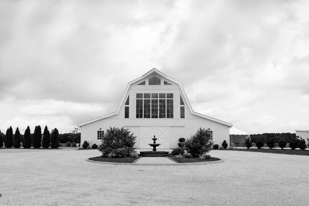 Black and white photo of white barn wedding venue with fountain centerpiece.