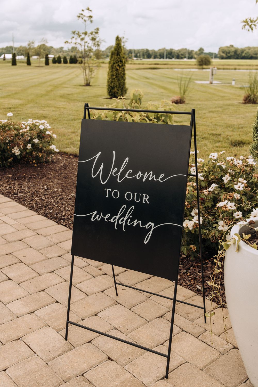 Black welcome to our wedding sign on easel at outdoor barn wedding venue.