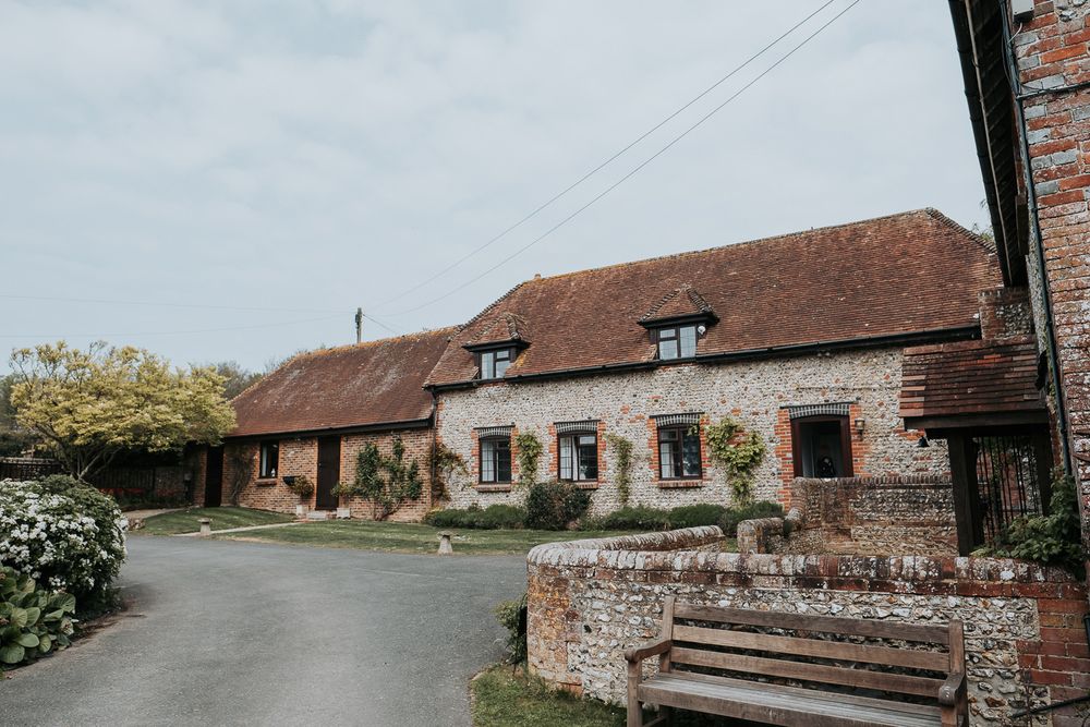A panoramic view of rustic brick farm buildings and barns with tiled roofs in the English countryside.