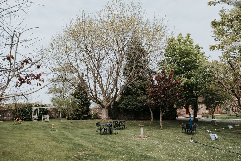 A panoramic view of a grassy hillside park with scattered trees and benches on a spring day.