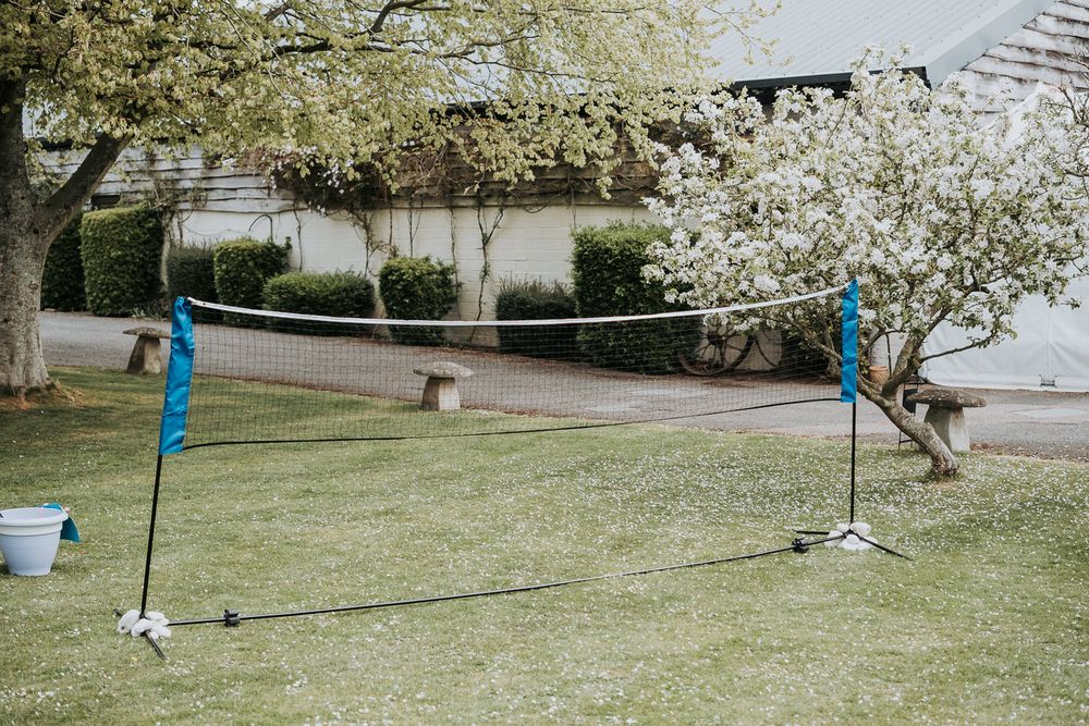 A clothesline stretches between trees with white spring blossoms in a sunny backyard garden setting.