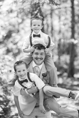 Joyful black and white portrait of wedding party members sharing a playful moment outdoors.