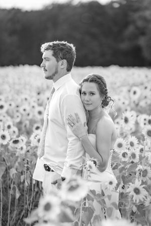 A couple poses together in a dreamy black and white portrait among sunflowers.
