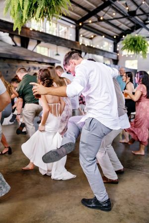 Wedding guests perform a fun line dance routine at an indoor reception venue.