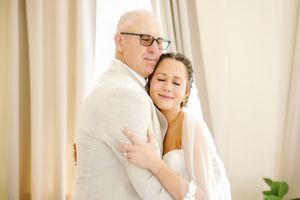 Tender embrace captured in soft natural light against cream background.