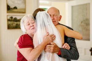 Emotional embrace between family members and a bride in white on her wedding day.