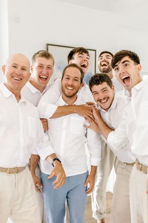 Groomsmen in white shirts and khakis sharing a candid laughing moment together.