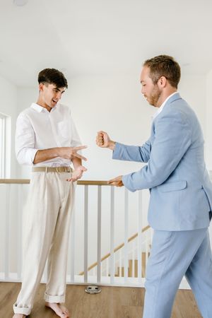 Two people in formal wear playfully interacting in a bright indoor setting.