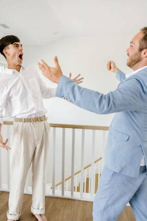 Two people in contrasting outfits sharing an animated moment by a staircase.