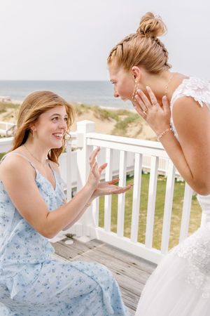 Sisters share a fun moment on a wooden deck overlooking the ocean.